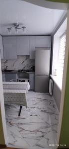 蒂拉斯波尔Просторная квартира в центре Тирасполя!的一间铺有大理石地板并配有白色橱柜的厨房