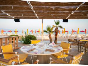 美西尼Buka Sandy Beach的一间带桌椅和海滩的餐厅