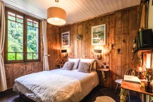 科特雷Les Ruisseaux的一间卧室设有木墙、一张床和一张书桌
