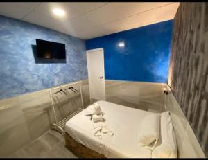 塞维利亚Hostal Avenida Andalucia的一间设有一张蓝色墙壁的床的房间