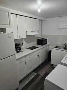 温尼伯River Park South - 2 Bedroom Basement Suite的白色的厨房配有白色橱柜和水槽