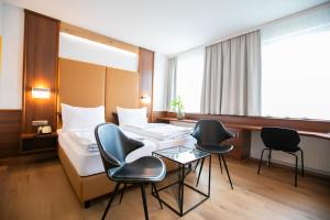 施韦夏特Das Reinisch Hotel & Restaurant的配有床、椅子和桌子的酒店客房