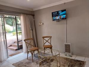 比勒陀利亚Lydiana Guesthouse的客厅配有两把椅子和墙上的电视