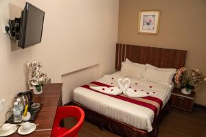 怡保Hotel Eastana Ipoh的一间卧室配有一张床和一张带红色椅子的书桌