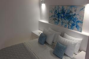 安坡里奥圣托里尼AB Green Living Santorini的客房配有带枕头的床和绘画作品