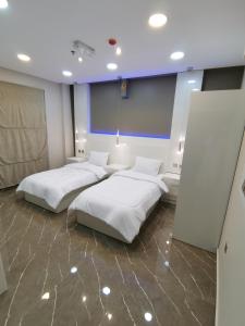 索哈尔Marina的配有白色床单的客房内的两张床