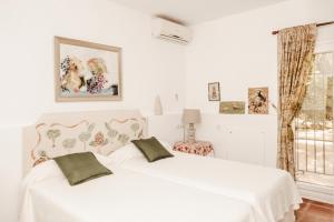 加的斯Casa Dehesa de las yeguas的一间卧室设有两张白色的床和窗户