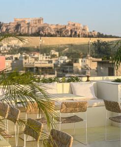 雅典Apollo Palm Hotel的一个带沙发和椅子的阳台,并享有城市美景。