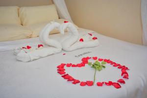 思由基茅Caphill Hotel的一张带毛巾的床和玫瑰制成的心