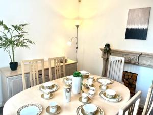 曼彻斯特Spacious 3 Bedroom House - Sleeps 5的一张木桌,上面有盘子和杯子