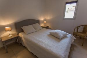 圣弗洛朗APPARTEMENT TERRASSE La Citadelle Appartements Saint Florent的一间卧室配有一张带两张桌子和一扇窗户的床。