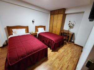 塔克纳Hotel Oceano Mit的酒店客房,配有两张带红色床单的床