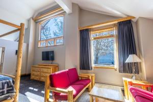班夫Brewster Mountain Lodge的一间卧室配有红色椅子、一张床和窗户