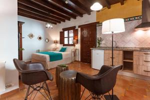 格拉纳达SUITES CASA DE LAS COLUMNAS的酒店客房,配有一张床和两把椅子