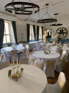 托斯特Saracens Head Hotel by Greene King Inns的宴会厅配有白色的桌子和白色的椅子