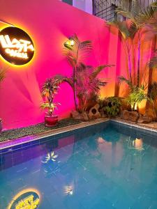 利马Llaqta Wasi的一座游泳池,位于粉红色的墙壁前,种植了植物