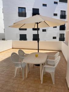 奎特里拉A Minha Praia的一张白色的桌子和椅子,配有雨伞