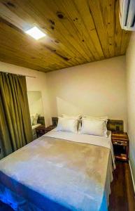 费尔南多 - 迪诺罗尼亚Vila Cris的一间卧室设有一张带木制天花板的大床
