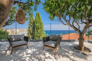 Saint-AntoineProche Monaco, vue mer, accès plage et jardin privatif的两把椅子坐在海边的树下