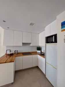 阿德耶Apartamento Vistas Paraiso的白色的厨房配有白色橱柜和冰箱。