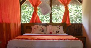 CuyavenusCaiman Lodge的一间卧室配有一张带红色窗帘的床和一扇窗户