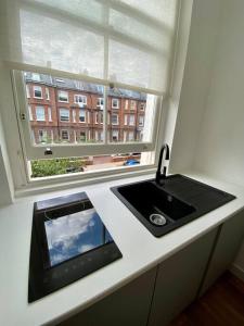 伦敦Studio for 3 near Regents Park n5的带水槽的厨房台面和窗户