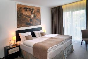 米哈洛夫采木森酒店的卧室配有一张大床,墙上挂有绘画作品