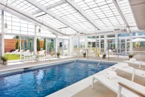 LeawoodElement Kansas City Overland Park的大型室内游泳池设有白色家具和窗户