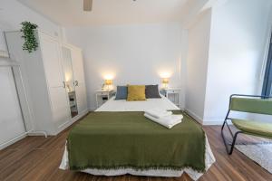 雷乌斯ApartamentosDnord的一间卧室配有一张带绿毯的床和一把椅子