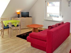 KröslinFerienwohnungen mit Balkon的客厅配有红色的沙发和桌子