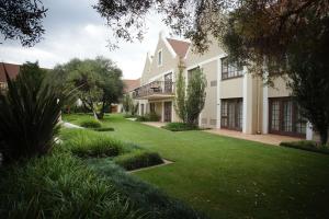 布隆方丹Southern Sun Bloemfontein的一座带绿色庭院的大型白色房屋