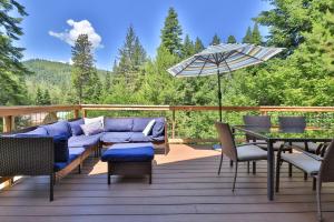 莱文沃思Leavenworth Cabin 3 Mi to Lake Wenatchee Hot Tub!的天井配有沙发、桌子和雨伞。