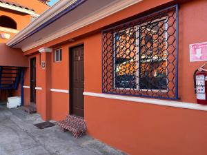 恩塞纳达港Hotel Hacienda的橙色的建筑,设有窗户和栅栏