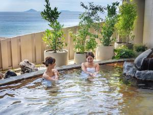 东伊豆町Atagawa Ocean Resort的两个女孩在热水浴缸中,在海洋里