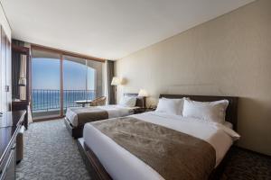 束草市马瑞蒙斯酒店的酒店客房设有两张床和大窗户。
