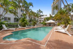 黄金海岸Bay Lodge - Private Apartments的一个带躺椅的游泳池,棕榈树