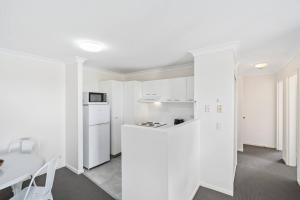 黄金海岸Bay Lodge - Private Apartments的白色的厨房配有白色的柜台和桌子