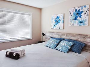 卡尔加里Calgary Gorgeous Single House close LRT&UC&Free Parking的一间卧室配有一张带蓝色枕头的床和一扇窗户。