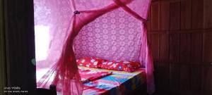 邦隆Farmer home stay & trekking的客房内的一张带红色枕头的天蓬床