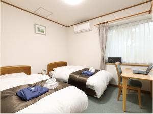 八幡平市Pension Hinode的酒店客房设有三张床和一张带笔记本电脑的书桌