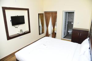 埃尔加德Hotel R Inn Yercaud的一间卧室配有一张床、一台电视和镜子