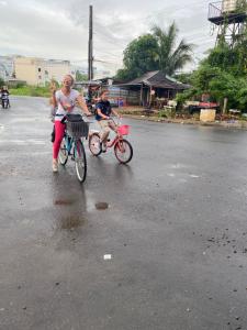 芹苴Mekong Farmstay CanTho - C.R Floating Market的街上的一辆女子和一辆儿童骑车