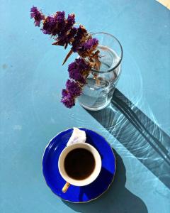 DūmāStone Cellars的一块蓝色的盘子,上面有一杯咖啡和花瓶