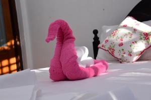 埃拉9 Hills Ella的一只粉红色的填充动物坐在床上