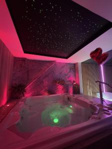 BonnevalLes Secrets Rooms - Bonneval - Love Room - Spa et Hammam Privatif的浴室配有带粉红色照明的大浴缸