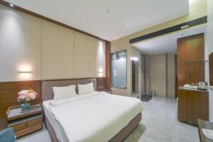 SāngliHotel Devgiri Inn and Restaurant的卧室配有一张白色大床和一张书桌