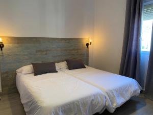 蒙地卡罗Hostal El Pinar的一间卧室配有带白色床单和枕头的床。