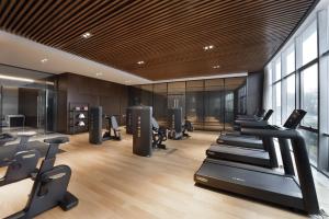 青岛青岛国际机场君廷酒店的健身房设有一排跑步机和有氧运动器材