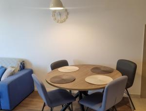 赫尔采格诺维Doxa M Apartments的一张桌子、四把椅子和一张蓝色的沙发