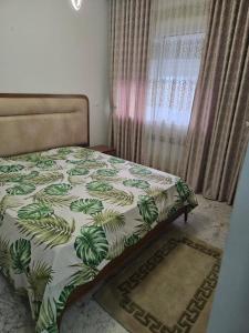 El AouinaBattouta22的一间卧室配有一张带绿色棉被的床和窗户。